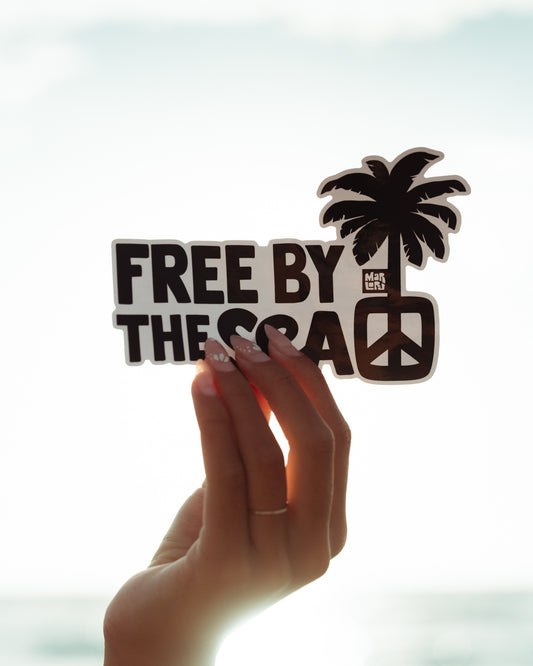 Free by the Sea Sticker by Marloru, held up against a bright ocean sky