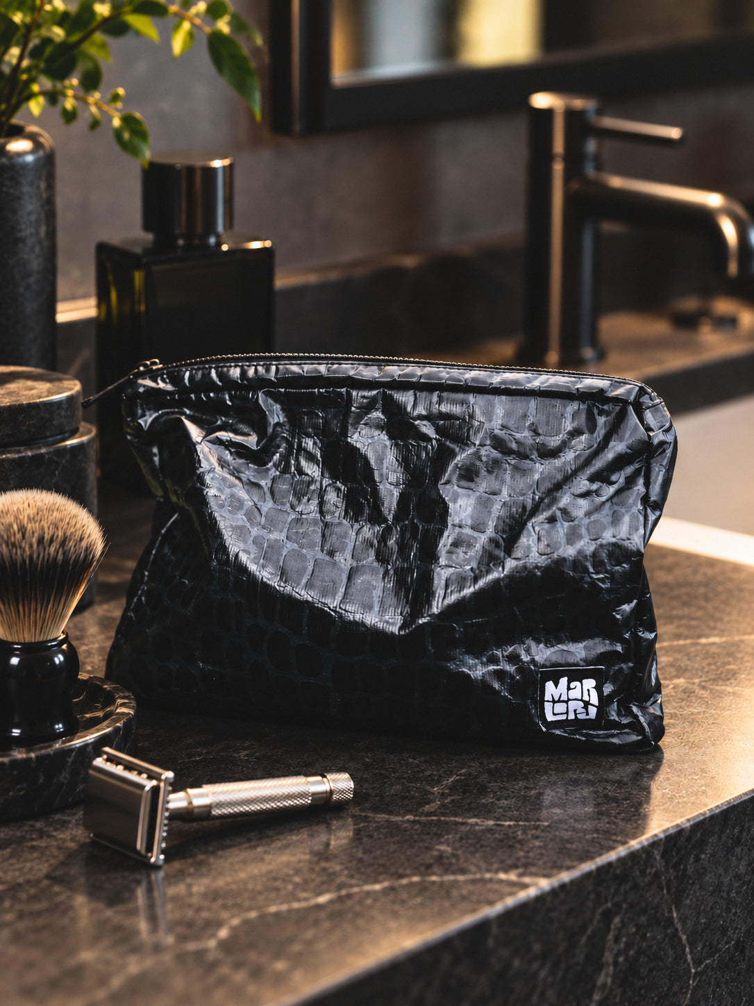 Gator Mid Pouch on a dark marble bathroom counter with a razor and shaving brush, a water-resistant toiletry pouch